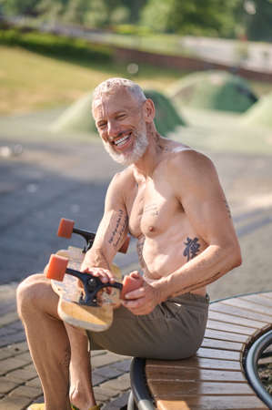 A man sitting and fixing details of his skateboardの写真素材