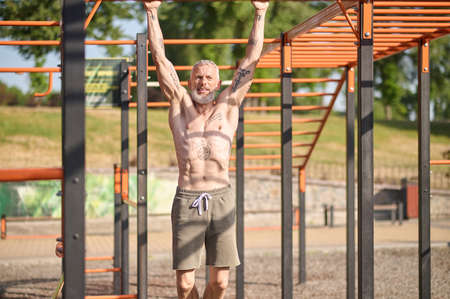 A gray-haired mature man having a workout on the open sports ground