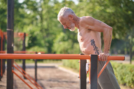 A mature gray-haired man exercising in the park