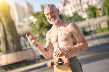 A half-naked skateboarder holding a skateboardの写真素材