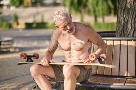 A man sitting and fixing details of his skateboard