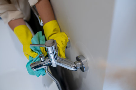 A service woman polishing faucet in the bathroomの写真素材
