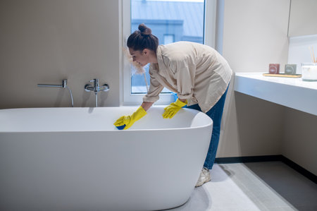 A woman doing cleaning at home and disinfecting the bathroom