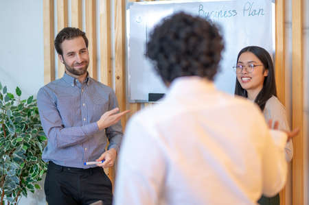 Three company employees discussing a business plant at the whiteboard