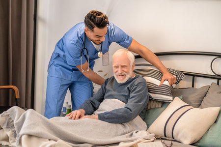 Healthcare worker helping a bedridden person sit up in bedの写真素材