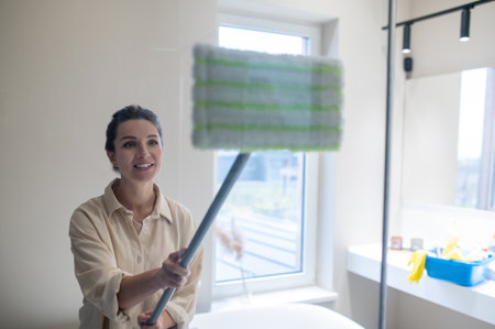 Young woman cleaning the sahower cabin and looking involvedの写真素材