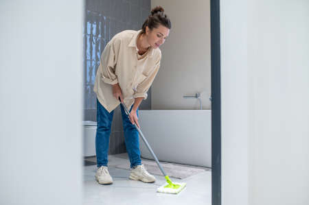 Young woman cleaning the floor at home