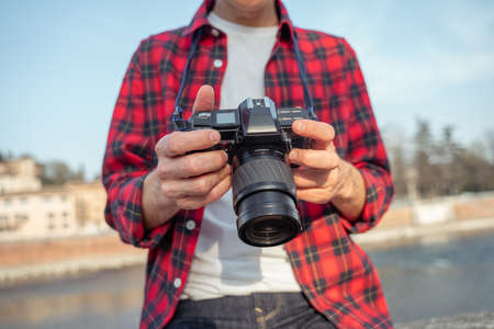 Male hands holding photo camera outdoorsの写真素材