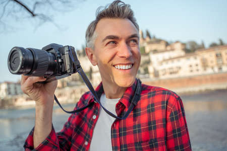 Man smiling to side holding camera