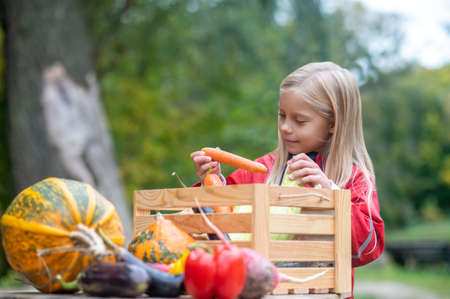 Long-haired blonde girl looking busy while sorting veggiesの写真素材