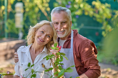 Man hugging woman smiling at camera in gardenの写真素材