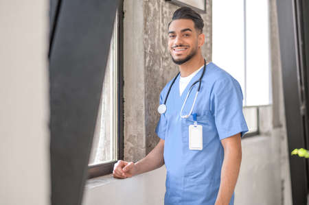 Joyful healthcare worker standing by the window and looking aheadの写真素材