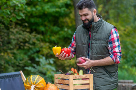 A man in plaid shirt and vest sitting in the yard