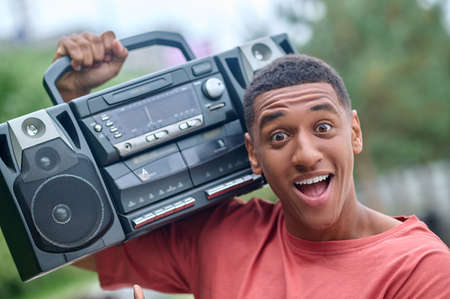 Guy with record-player on shoulder enthusiastically looking at cameraの写真素材