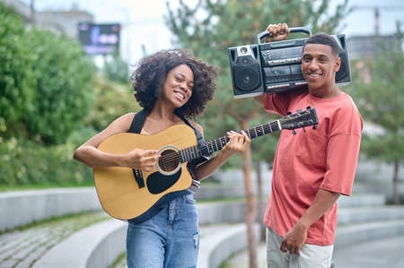 Girl with guitar guy with record-player looking at cameraの写真素材
