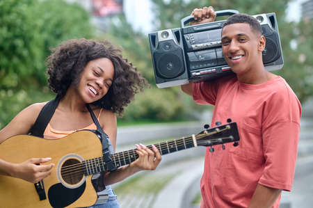Girl with guitar and guy smiling at cameraの写真素材