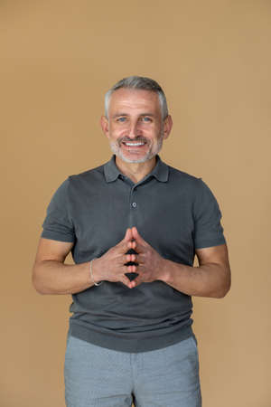 A man in a grey tshirt looking confident and smiling