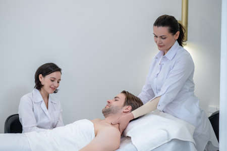 Young man having neck and shoulders massage in a spa salonの写真素材