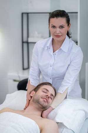 Young man having neck and shoulders massage in a spa salonの写真素材