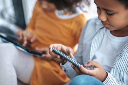 Two kids spending time online using their devicesの写真素材