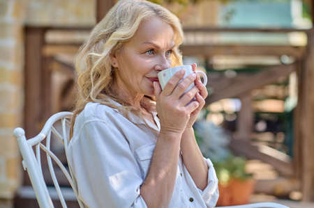 A blonde woman having coffee and smilingの写真素材