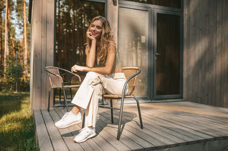 Pretty lady resting in the armchair on the wooden porchの写真素材