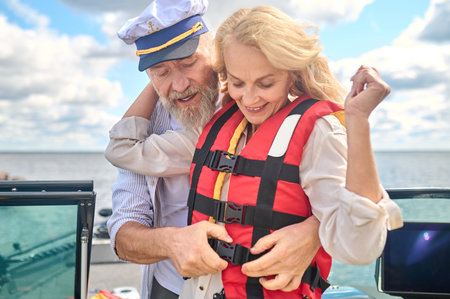 A man in helping a blonde woman to put on the life vest