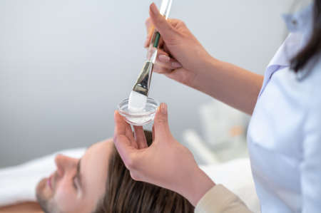 Cosmetologist holding a brush for applying cream on a clients faceの写真素材