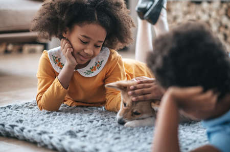 Kids lying on the floor next to their pet and looking happyの写真素材
