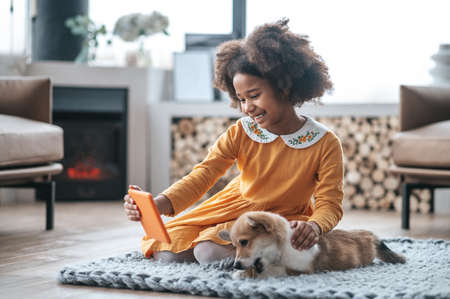 A pretty smiling girl with a puppy making selfie on her deviceの写真素材