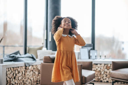 Cute curly-haired girl looking cheerful and happyの写真素材