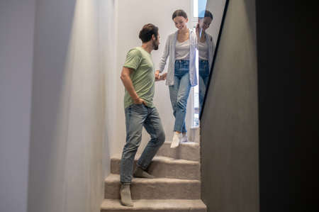 Man supporting woman walking down stairs at homeの写真素材