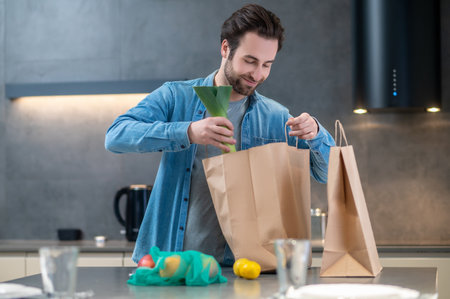 Satisfied man looking into bag of groceriesの写真素材