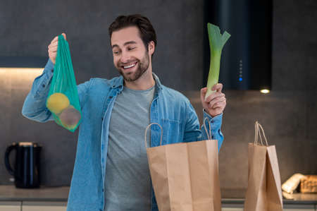 Happy man looking at fruits in raised handの写真素材