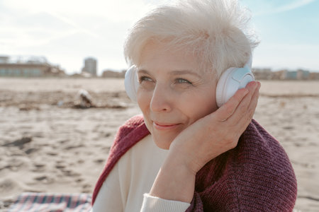 Pleased elderly lady listening to favorite songs outdoorsの写真素材