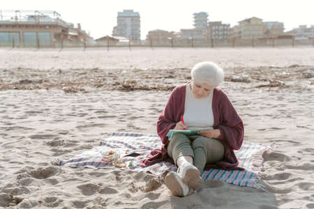 Focused gray-haired woman taking notes in her diaryの写真素材