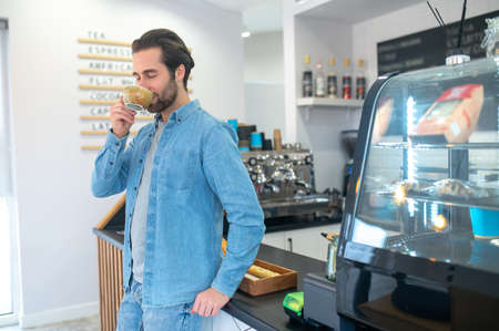Man standing drinking coffee with closed eyesの写真素材