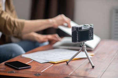 Camera and smartphone on table and hands opening laptop