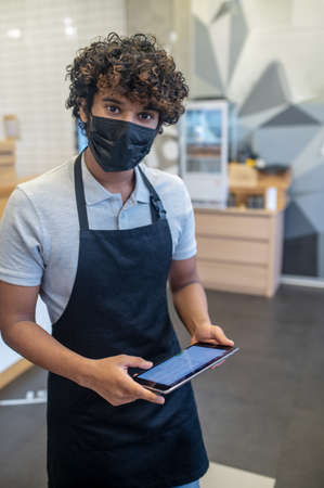 Man in protective mask with tablet looking at camera