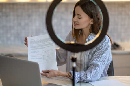 Woman sideways to camera showing document on laptop screenの写真素材