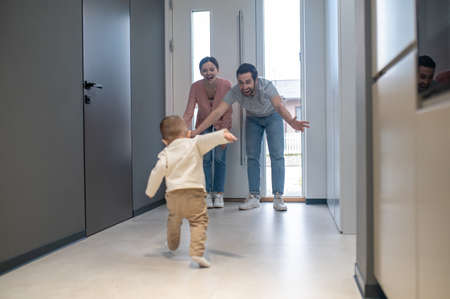 Little boy doing his first steps to his parentsの写真素材