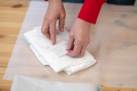 Top view of hands putting card into folded shirt