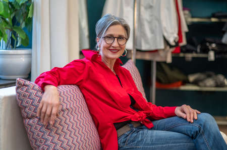 Woman confidently looking at camera sitting on sofaの写真素材