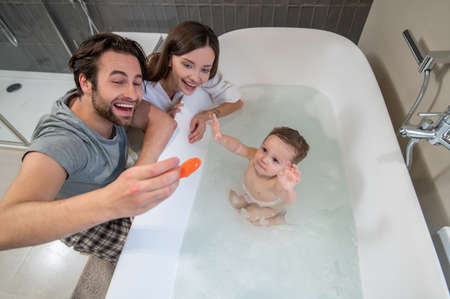 Top view of parents playing with baby in bathtubの写真素材