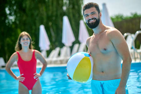 Joyous guy and a woman in the outdoor swimming pool