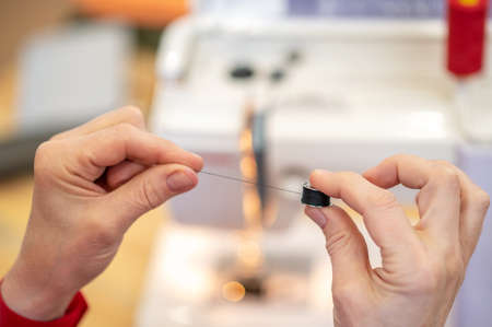 Hands holding sewing spool of threadの写真素材