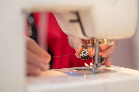 Hands preparing sewing machine for sewing