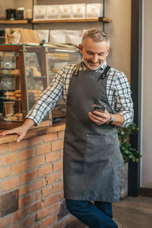 Man standing near bar looking at smartphoneの写真素材