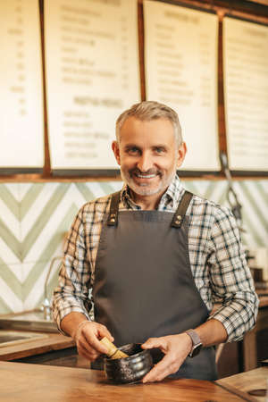 Man standing at bar cooking looking at camera