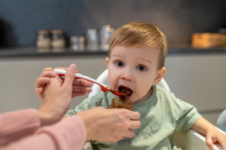 Parents feeding a cute baby boy in the kitchenの写真素材
